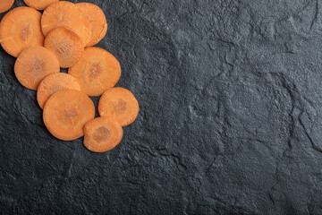 Fresh organic raw sliced carrots on black background