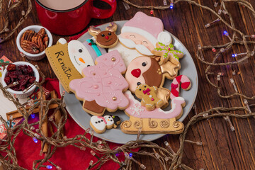 Christmas gingerbread cookies on vintage plate, hot chocolate, with color lights on rustic table.