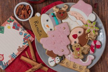 Fototapeta na wymiar Christmas gingerbread cookies on vintage plate, hot chocolate, with color lights on rustic table.