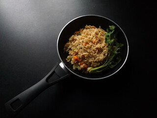 Traditional black pan of instant noodles dark background