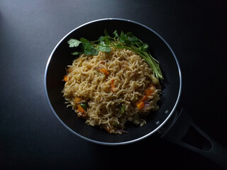 Traditional black pan of instant noodles dark background
