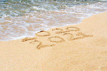 2021 and 2020 Numbers written on sand. Beach ocean wave on background. New Year concept photo