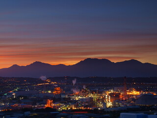 Fototapeta na wymiar factories and mountain silhouettes at dawn