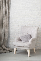 soft armchair near white brick wall with gray curtain. Arm-chair with gray upholstery