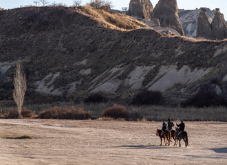 People doing safari with beautiful horses in Cappadocia with the scenery of fairy chimneys