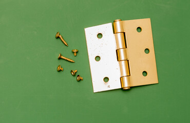 A top down shot of a brass window hinge isolated against a green cutting board. 