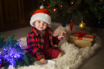 a child in red clothes is sitting waiting for the new year. the concept of celebrating Christmas at midnight. holiday costume