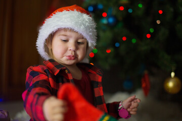 a child in red clothes is sitting waiting for the new year. the concept of celebrating Christmas at midnight. holiday costume
