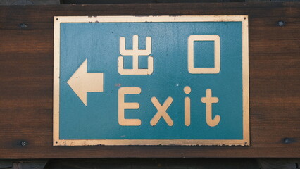 old japanese exit sign with gold letters on a blue metal background