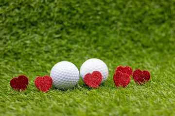 Naklejka premium Golf ball for Valentine's Day with red heart are on green grass with love