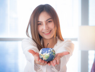 World food day concept: Selective focus blue earth globe of apple, Asian woman giving fruit. Elements of this image furnished by NASA