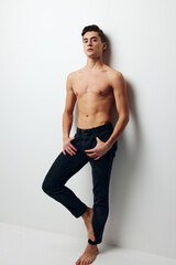 Fototapeta premium A man with a raised leg stands near the wall, front view