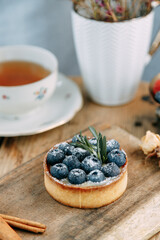 Cake with buttercream and blueberries on a plate. Close-up tartlet with berries and milk.