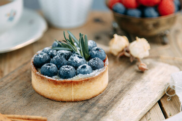 Cake with buttercream and blueberries on a plate. Close-up tartlet with berries and milk.