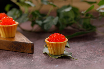 Appetizing tartlets with red caviar on a decorative board for serving. Holiday concept. Close-up.