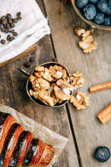 Chocolate croissant on a wooden table with walnuts. Walnuts close-up.