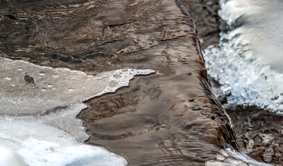 Water and foam close-up on a small waterfall of the river in winter
