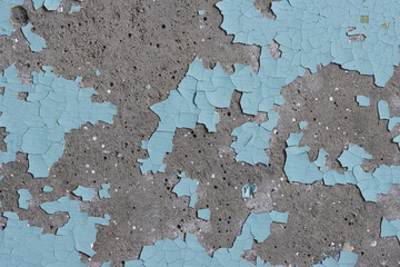 Blue peeling paint on the wall. Old concrete wall with cracked flaking paint. Weathered rough painted surface with patterns of cracks and peeling. High resolution texture for background and design.