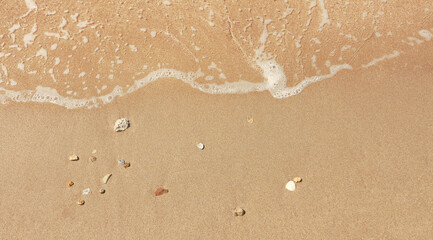 Fototapeta na wymiar Sand on the beach with champagne color and a group of small stones. Close up top view.