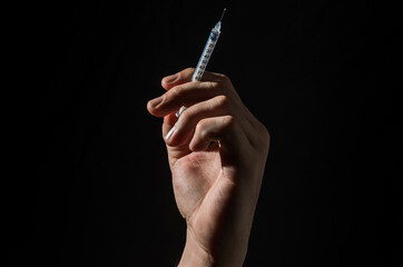 Hand with injection syringe on black background	