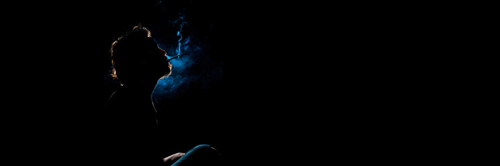 Colored silhouette of a smoking man on dark background. Banner panoramic. Copy space for text message.