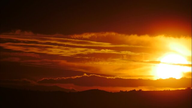 Skyscape. Burning sky, dark stormy clouds moving over coast landscape. Red orange color sunset over sea. Capi Corb, Mediterranean coast of Spain. Time lapse
