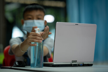 Alcohol gel and kids washing hand for protect coronavirus and wearing mask for learning in classroom of school, Asian children holding bottle alcohol gel, kid playing laptop on table education concept