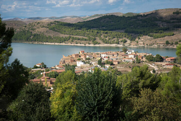 Fototapeta na wymiar Drone view of buildings and hills surrounded by water in Nuevalos, Spain