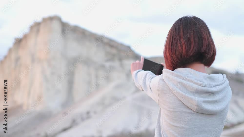 Poster explorer young woman taking a photo or shooting a video of ak-kaya white rock, crimea. concept of tr