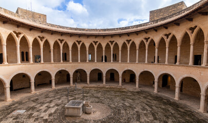 Fototapeta na wymiar Arcades of the inner courtyard of Bellver castle with a water well in the middle in Mallorca, Spain