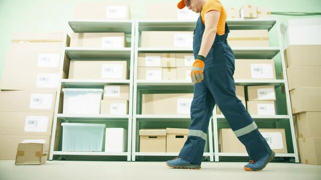 Funny careless neglectful warehouse worker kicks a parcel on the storage floor