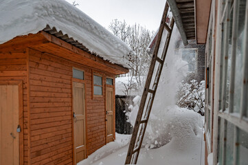 Real Russian winter, when frost and a lot of snow, in the country village, with small houses, dumping snow from the roof of a house	

