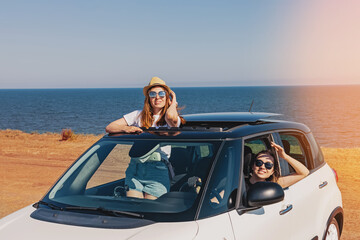 Two happy female friends enjoying road trip.