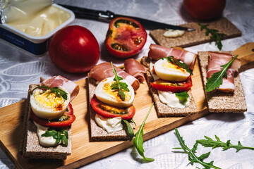 crispbreads with smoked ham, tomatoes and eggs on a cutting board