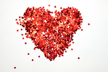 Fototapeta na wymiar Flat lay heart made of lots of small red glitter hearts as symbol of love for valentine day
