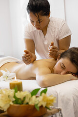Obraz na płótnie Canvas Young adult woman receives body massage at beauty salon