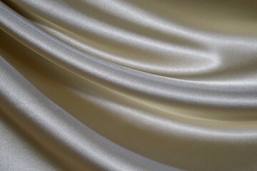 Abstract gold background. Beautiful silk satin cloth texture background. Soft wavy folds on shiny...