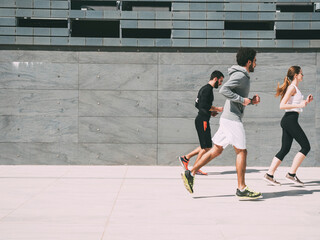 three friends athletes jogging in a modern building district