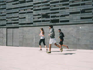 three friends athletes jogging in a modern building district