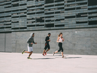 three friends athletes jogging in a modern building district