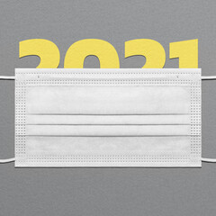 Colors of the year - PANTONE 17-5104 Ultimate Gray and 13-0647 Illuminating. Figure 2021 under a medical mask on a dark paper textured background. 