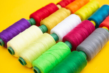 Color sewing threads on yellow background 