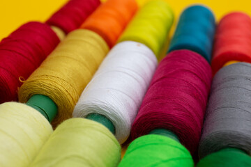 Color sewing threads on yellow background 