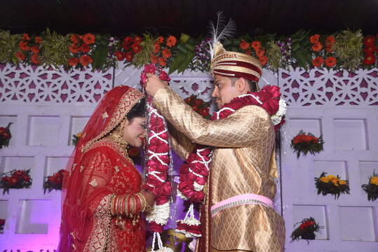 Bride and groom putting garland as a ceremonial proceeding as per Hindu Marriage Rituals and posing for the photograph. The Garland and is made of roses and white flower buds
