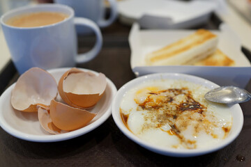 Toasted bread with half boiled egg served with a cup of milk tea, Asian breakfast.