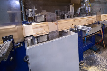Glued laminated timber lies in a woodworking machine. Production of building materials from wood.