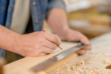 Close up man's hands taking measurement of a wooden plank