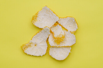 Orange or tangerine peel isolated on yellow background. Vitamin C, skin beauty and health concept