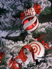 close up red and white christmas tree decorations on a snow covered tree