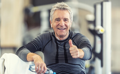 Fototapeta na wymiar Man with grey hair holds thumbs up after a workout as staying fit regardless of age